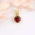 Macro détaillée d'un pendentif doré avec zircone rouge ronde sertie de quatre griffes - Rouge Foncé