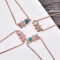 Detailed close-up of rose gold astronaut bracelets with colorful opal stones and zircon stones - Blue Opal (Bracelet) / Rose Gold Girl