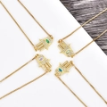 Detalle de los colgantes de mano de Hamsa con cadenas de caja y gemas de colores - Pulsera de oro