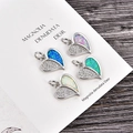 Gros plan de quatre breloques cœur avec zircone et détails d'incrustation d'opale colorée - Opale bleue / Coeur en Platine