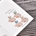 Macro detail of rabbit jewelry charms with white cubic zirconia and colored opal inlay - Blue Opal / Rose Gold Rabbit
