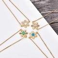 Dettaglio di collane a fiocco di neve dorate con opali colorati su fondo in legno - Bracciale Regolabile Fiocco Oro