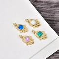 Detailed view of four Hamsa Hand pendants with colorful opal inlays on wood background - Gold Hamsa-Blue Opal