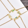 Four lizard pendants with colorful opal stones on gold-plated box chains shown on wood - Blue Opal / Gold Gecko Bracelet