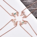 Makroaufnahme von roségoldenen Pferdependeln mit Opal-Inlay an feinen Boxketten - Roségoldenes Pferd Armband