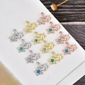 Macro shot of turtle and starfish pendants featuring opal inlay and sparkling zircons - Yellow Gold Star with Turtle