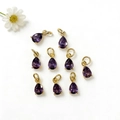 Dettaglio di nove ciondoli in zircone viola a goccia con anelli dorati per gioielli - Viola