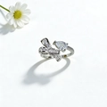 Makroaufnahme von Silberbogenring mit birnenförmigem Stein und Pavé auf weißem Gänseblümchen - Schleife Wassertropfen-Stil / Silber