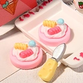 Nahaufnahme von Miniatur-Resin-Sahnekuchen-Anhängern und Käsemesser für DIY-Basteln - Rosa Doppelrollenkuchen