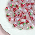 Detailed close-up of acrylic strawberry beads with glitter inside on a ceramic tray - Transparent Pink Bead with Red Strawberry