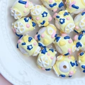 Macro shot of yellow acrylic hand-painted beads with floral patterns in a ceramic plate - White Bead with Yellow Cream Lemon and Blue Flower