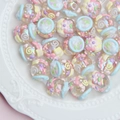 Macro detail of macaron colored acrylic beads with embossed patterns and pearl finish - Transparent Bead with Blue Ring and Hi Text