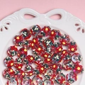 Primer plano de cuentas navideñas coloridas con motivos florales en un plato de cerámica - Vendido por unidad / Cuenta Transparente con Crema Rojo Verde Amarillo Lazo Rojo Estrella Amarilla