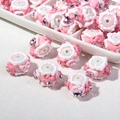 Makro-Detail von rosa DIY-Blumenperlen mit herzförmigen Strasssteinen auf Stoff - Weiße Perle + Rosa Blume + Herz Strass