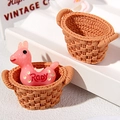 Close-up of a pink resin Rody horse toy with two miniature brown woven texture baskets - Oval (Empty Basket) / Brown