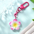Close-up of pink gradient frangipani keychain with metallic D-ring on blue water base - Rose Red