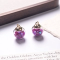 Macro shot of glass ball pendants with purple heart sequins and golden metal ring caps - Purple