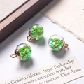 Close-up of glass orb charms with green heart sequins and gold metal caps for DIY jewelry - Grass Green