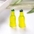 Macro view of two miniature translucent yellow-green resin soda bottles for DIY dollhouses - Green