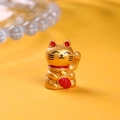 Detailed close-up of a mini golden Maneki Neko figurine with red fortune symbol and bell - Single Piece / Gold (Left Hand Raised)