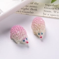Vista macro de dos mini figuras de erizo de resina rosa y crema con texturas en 3D - Violeta Claro