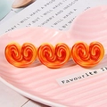 Graziosa clip per capelli con spirali di pasticceria arancioni su un piatto rosa - Biscotto a Cuore