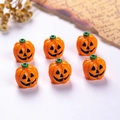 Detailed macro view of 6 resin Halloween pumpkin charms with jack-o-lantern faces - Orange