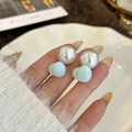 Detailed view of hand-held pearl earrings with blue heart-shaped flocked charms - Blue