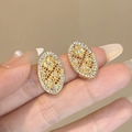 Macro dettagliata di orecchini a perno ovali dorati con motivi floreali vintage e zirconi - Petalo in Strass Ovale (E4397-1)