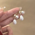 Dettaglio di orecchini d'oro con perle tonde e a goccia tenuti elegantemente in mano - Piccola Goccia d'Acqua Oro (E2372-1)