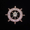 Primer plano detallado de un broche de timón en oro rosa con brillantes cristales claros - Oro rosa