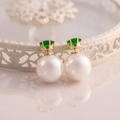 Detail of crown setting with green emerald gemstone and large white round pearl earring - Green