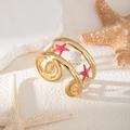 Dettaglio del bracciale dorato regolabile con stella marina rossa e conchiglia su sabbia - Stella Marina Conchiglia Rosso (S987)