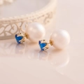 Macro detail of double-sided pearl earrings featuring a blue heart-shaped gemstone - Sapphire Blue