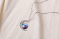 Detailed shot of a silver moon necklace with colorful nebula glass gem and hollow patterns - Colorful Nebula Pattern (X629-7)