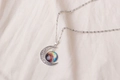 Macro shot of silver crescent moon pendant with nebula glass on beige linen fabric - Colorful Starry Sky Pattern (X629-4)