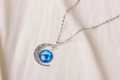 Close-up of crescent moon pendant with blue starry sky glass ball on linen background - Blue Starry Sky Pattern (X629-12)