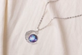 Detailed macro of a crescent moon pendant with galaxy nebula gemstone on soft fabric - Purple-Blue Nebula Pattern (X629-1)