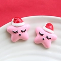 Gros plan de charms étoiles de Noël roses en résine avec expressions et bonnets de fête - Rose