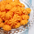 Macro shot of orange star-shaped resin charms with textured radial ridges in a glass tray - Cream Cookie
