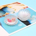Vue macro d'un coquillage nacré en résine avec une figurine de sirène rose endormie - Blanc Brillant