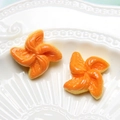 Macro shot of orange flower resin accessories on a decorative white ceramic tray - Windmill Bread