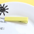 Detail of light yellow matte duckbill clip on a white ceramic plate with sunny accents - Matte Yellow