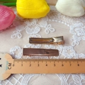Macro detail of 4.8cm gold plated metal duckbill hair clips on white lace fabric - Electroplated Gold