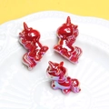 Vue détaillée de trois perles licornes en acrylique rouge iridescent dans un plat - Trou 3mm / Rouge