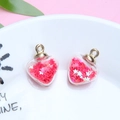 Close-up of heart-shaped glass charms with red star sequins and gold metal rings - 1.8 x 2.4cm / Red