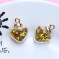 Detail view of heart-shaped glass pendants filled with golden star sequins and metal caps - 1.8 x 2.4cm / Gold