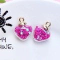 Close-up of heart-shaped glass pendants filled with rose red star sequins and gold ring - 1.8 x 2.4cm / Rose Red