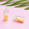 Dettaglio di mini bottiglie di vetro con paillettes a stella gialla e tappi per gioielli fai-da-te - Arancione