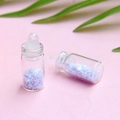 Macro di mini bottiglie dei desideri con paillettes a stella viola su sfondo rosa - Lavanda